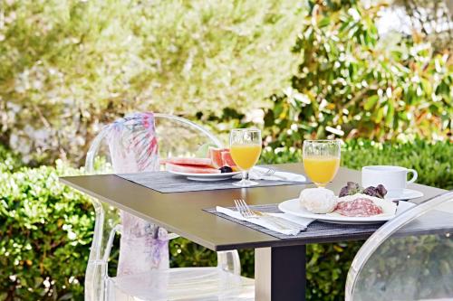 een tafel met een bord eten en twee glazen sinaasappelsap bij Globales Cala Blanca in Cala Blanca
