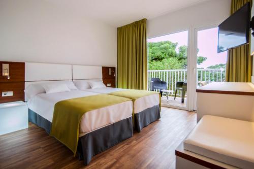 Habitación de hotel con cama y balcón en Globales Cala Blanca, en Cala Blanca