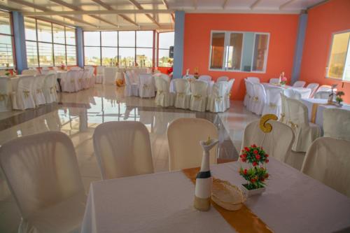 un salón de banquetes con mesas blancas y sillas blancas en Hotel Sea World, en San Jacinto