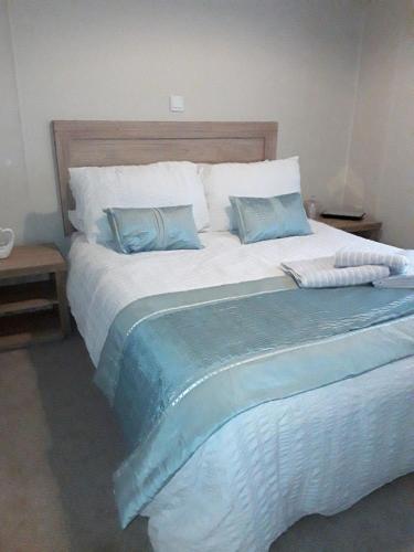 a large bed with blue pillows in a bedroom at Clearwater lodge Widemouth sands in Poundstock