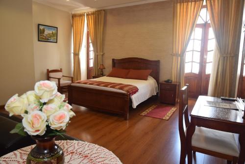 um quarto com uma cama e uma mesa com um vaso de flores em Hotel Casa Montero em Quito