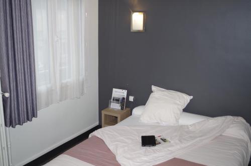 a bedroom with a bed with a book on it at The Originals City, Hôtel Le Savoy, Caen in Caen