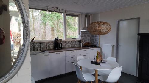 a kitchen with a white table and white chairs at Bungalow, vrijstaand, het Vosseven nr 38 in Stramproy