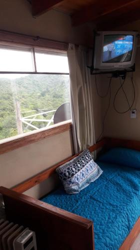 a small room with a bed with a television and a pillow at Mirador del Valle in Valle Hermoso