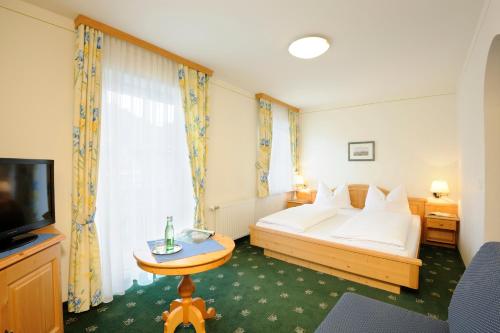 a hotel room with a bed and a television at Frühstückspension Huber in Fuschl am See