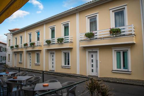 a building with tables and chairs in front of it at Costa & Isaias Apartamentos in Angra do Heroísmo