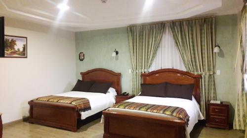 a bedroom with two beds and a window at Hotel Casa Montero in Quito
