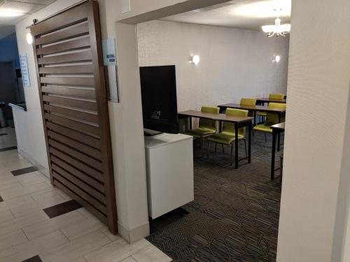 a waiting room with tables and a tv and a door at Holiday Inn Express Venice by IHG in Venice