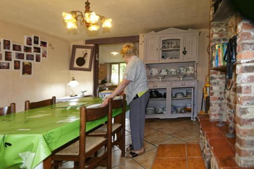 Eine Frau steht in einer Küche mit einem Tisch in der Unterkunft Gîte Du Cheval De Renfort in Ohis