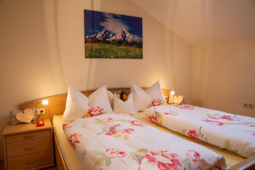 a bedroom with two beds with white sheets and pink flowers at Fewo Boigs - Haus am Wandei in Bischofswiesen