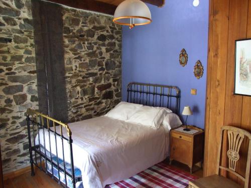 a bedroom with a bed and a stone wall at Casa Trallera in Colinas del Campo de Martín Moro