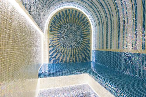 a bathroom with a tub with a patterned wall at Carmencita Studio B14 with pool & gym in Limassol