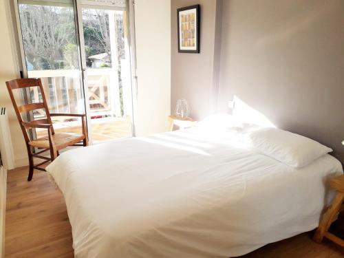 - un lit blanc dans une chambre avec une chaise et une fenêtre dans l'établissement ST ARNAUD Appartement Calme Parking proche Plage, à Arcachon