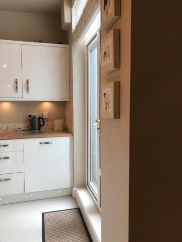 a kitchen with white cabinets and a window at Cosy house set in historic town of Clitheroe in Clitheroe
