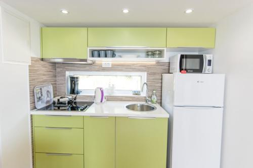 eine Küche mit grünen Schränken und einem weißen Kühlschrank in der Unterkunft Mobile home Opal 2 in Biograd na Moru