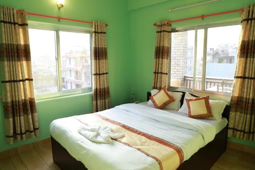a bedroom with a bed with green walls and windows at Hotel Pokhara Paradise in Pokhara