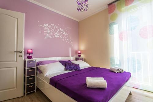 a bedroom with a purple bed and a window at Apartment Songbird in Biograd na Moru