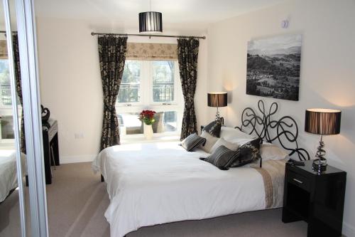 a bedroom with a large white bed and a window at Luxury riverside apartment in Kendal in Kendal