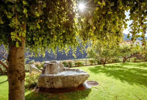 a stone bench sitting under a tree in a park at Hotel Chavalatsch in Tubre