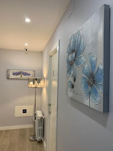 un pasillo con una pintura de flores azules en la pared en La Rosa Azul Rooms, en Ponferrada