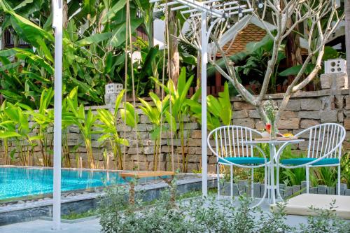 a table and chairs next to a swimming pool at Santorin HoiAn Villa in Hoi An
