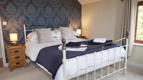 Oak Lodge B&B في بود: غرفة نوم بسرير كبير وملاءات زرقاء وبيضاء