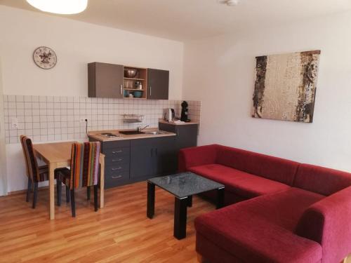 a living room with a red couch and a kitchen at Ferienwohnung - Apartment mit Balkon in Halle-Saale, Trotha in Halle an der Saale
