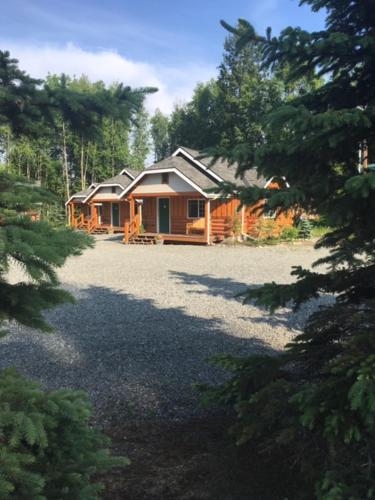 a house with a tree and some trees at Denali Fireside Cabin & Suites in Talkeetna