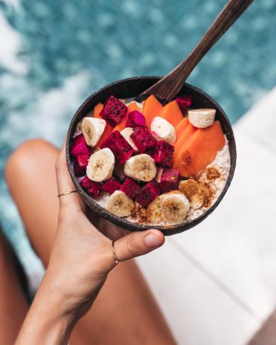 a hand holding a bowl of food with fruit at The Ellysian Boutique Hotel in Placencia Village