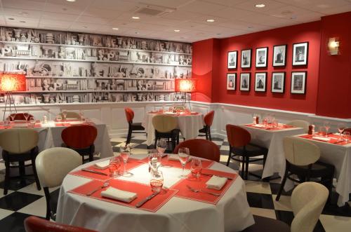 a restaurant with white tables and chairs and red walls at Les Maritonnes Parc & Vignoble in Romanèche-Thorins
