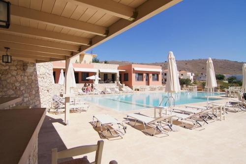 a swimming pool with lounge chairs and umbrellas at Angelica-Sea & Mountain View in Georgioupolis