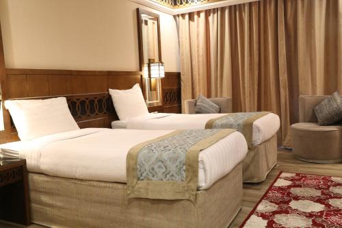 a hotel room with two beds and a chair at Violet Al Azizia Hotel MASJID Al Qatari in Makkah