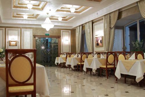 ein Restaurant mit Tischen und Stühlen in einem Zimmer in der Unterkunft Hotel Aristokrat in Poltawa