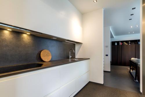 a kitchen with white cabinets and a black wall at Marvelous Lake Destination eco-friendly villa in Brienno