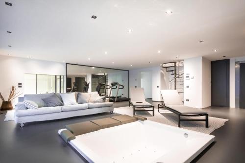 a living room with a white couch and chairs at Marvelous Lake Destination eco-friendly villa in Brienno