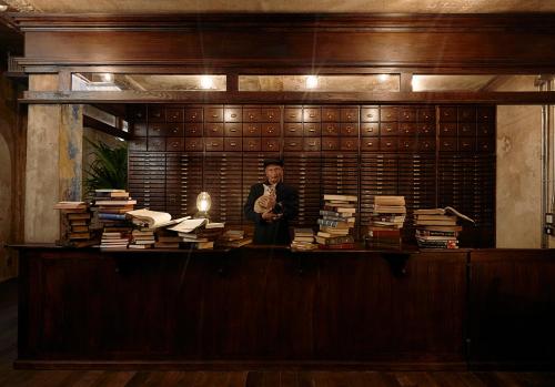 a man standing in a room filled with books at The Mustang Blu in Bangkok