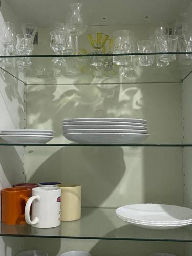 una estantería de cristal con platos y tazas y platos. en Residences Fama, en Mbour