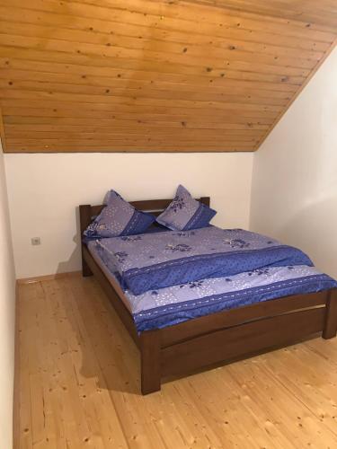 a bed in a room with a wooden ceiling at Котедж in Podobovets