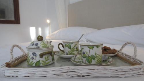 a tray with three cups and saucers on a bed at B&B Casa Soresina in Offagna