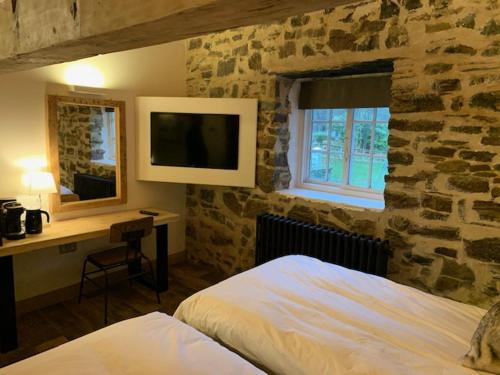 a bedroom with a stone wall with a bed and a desk at Trail Lodge in Ballasalla