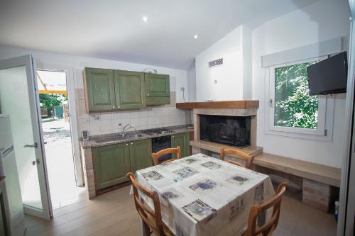 a kitchen with green cabinets and a table with chairs at Appartamenti & Bungalows Luca Angiolin in Cavallino-Treporti