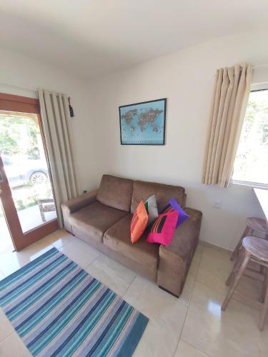 a living room with a brown couch with colorful pillows at Pousada Origin in Guarda do Embaú