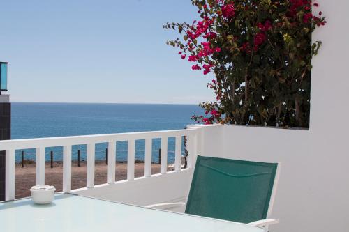 a table and a chair on a balcony with the ocean at Apartamentos Juan Benítez in El Cotillo