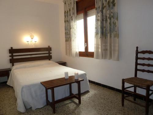 a bedroom with a bed and a chair and a window at Villa Service - Apartamentos Aransol in El Vendrell