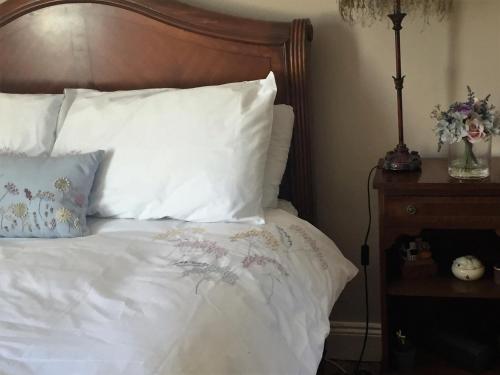 a bed with white sheets and pillows and a wooden headboard at Perfect getaway, seafront home in Bangor