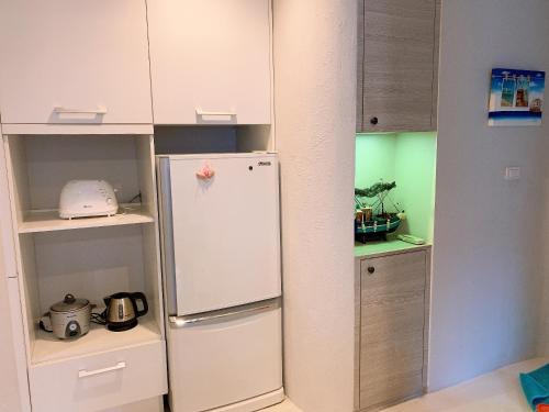 a kitchen with a white refrigerator and cabinets at Chelona huahin beachfront condominium in Khao Tao
