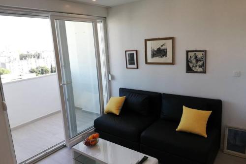 a black couch with yellow pillows in a living room at Apartment Altitudo Split sea and city view terrace comfortable and new in Split