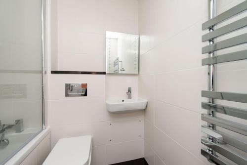 bagno bianco con lavandino e specchio di Mulberry Flat 6 - Two bedroom 3rd floor by City Living London a Londra