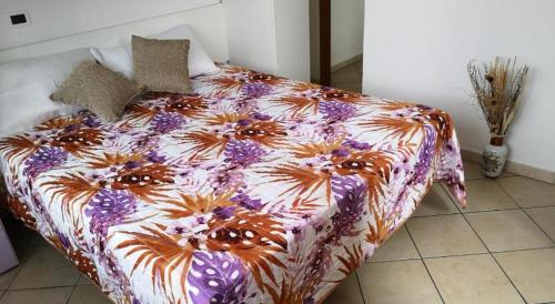 a bed with a colorful comforter with flowers on it at Marina Beach Blu in Porto Garibaldi