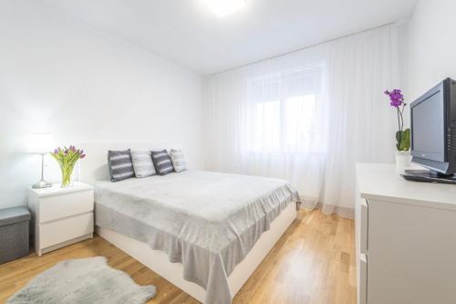ein weißes Schlafzimmer mit einem Bett und einem Flachbild-TV in der Unterkunft Anna’s lovely Home in Sighişoara
